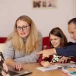 A family learning together with a laptop at home, emphasizing collaboration and education.